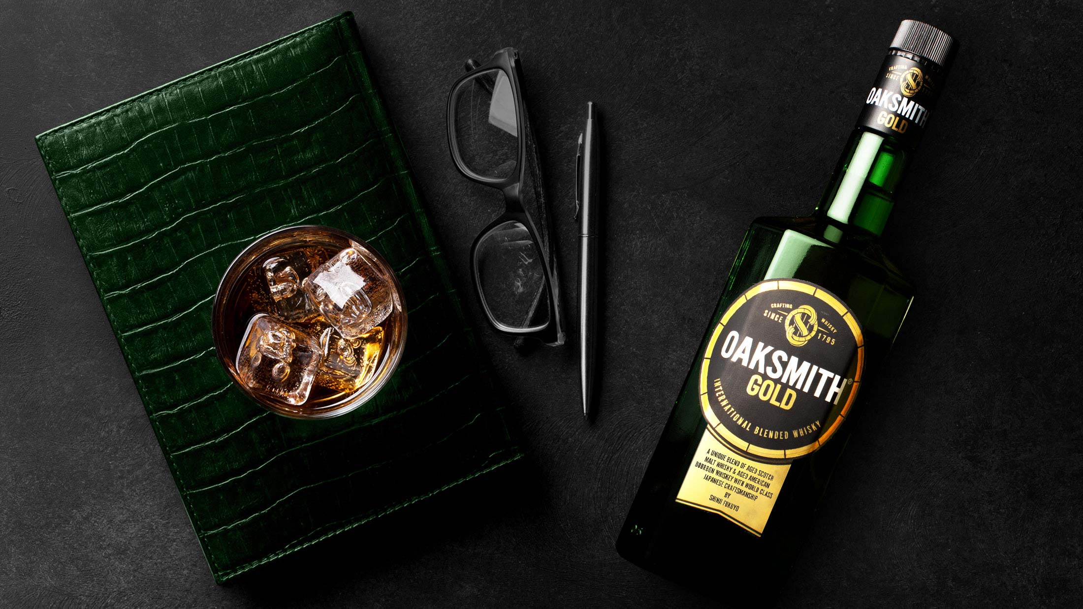 oaksmith gold premium whiskey with book, spectacles and pen